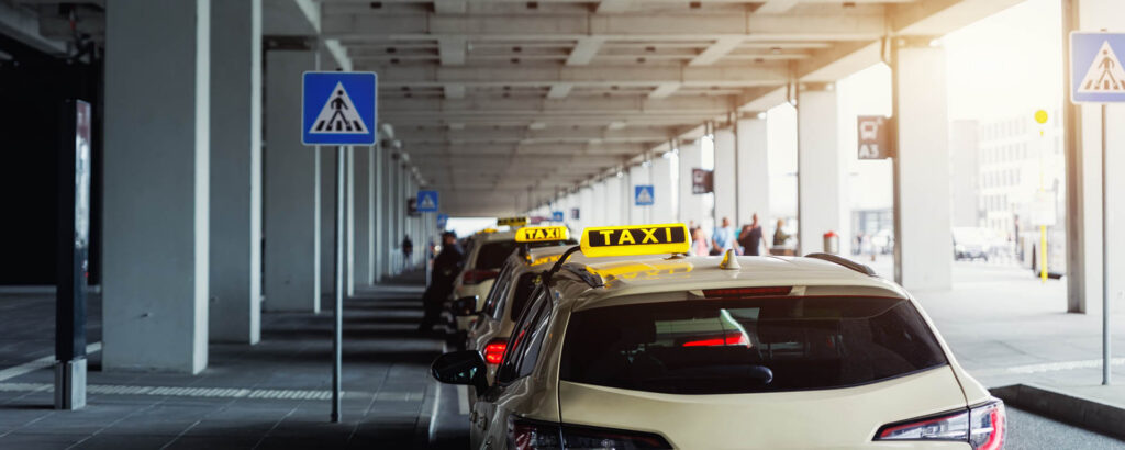 Taxi car Queue yellow taxi symbol  on roof stand waiting at parking of airport terminal or railway station Under Concrete Structure Transportation Hub. Urban street transportation comfort service.